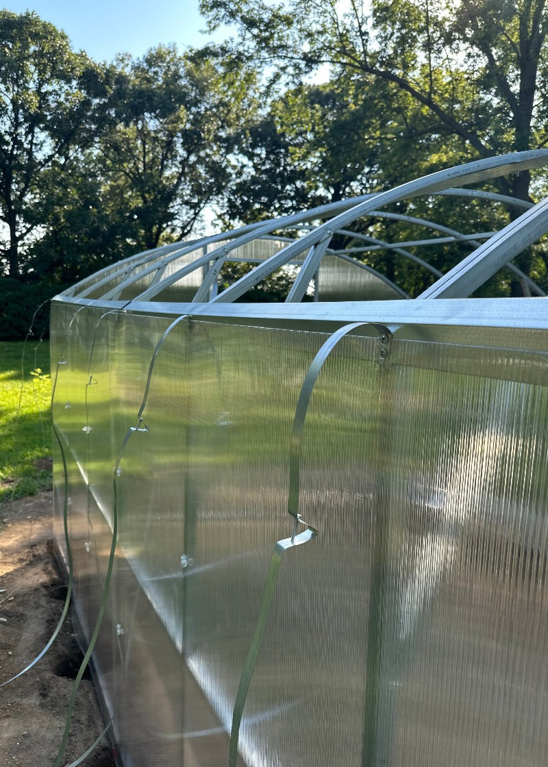 Heavy-duty greenhouse kit with galvanized steel frame and polycarbonate twin walls, designed to withstand harsh weather conditions.