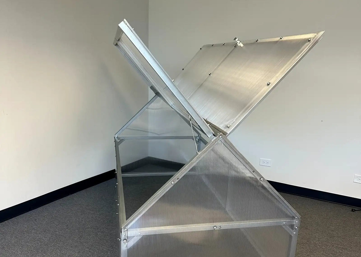 A silver aluminum greenhouse with a hinged lid that is open